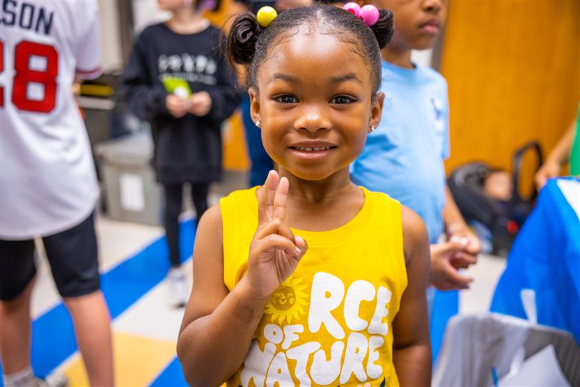 A girl wearing a yellow shirt smiles